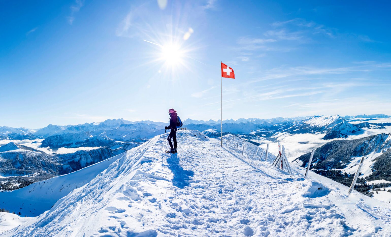 winter sports: snow shoe hiker a the summit of the snowy mountain in the swiss alps. panoramic switzerland mountain range